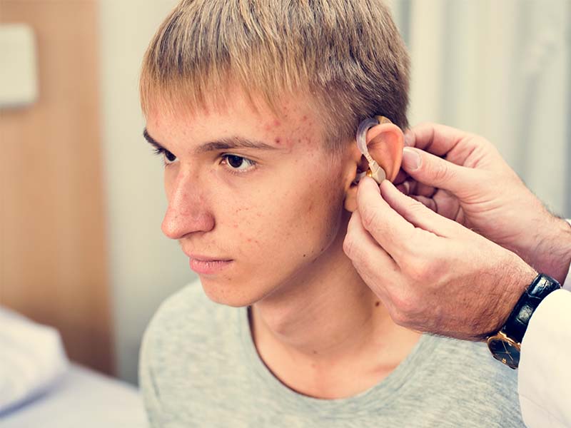 Bilde av tenåringsgutt med nedsatt hørsel som får tilpasset høreapparat.